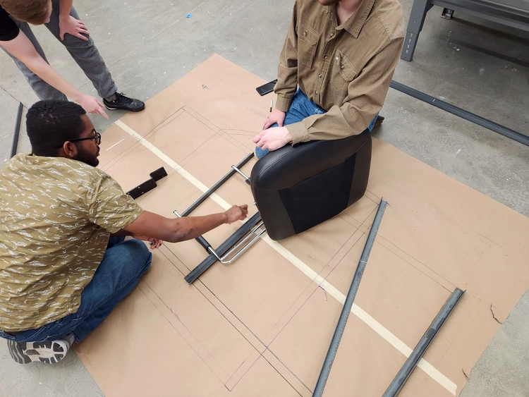 Photo of Caden, Andrew, and Felipe laying out parts for the frame's base layer.
