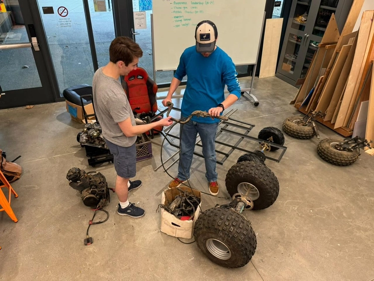 Photo of Caden and Jacob discussing how to integrate the ATV parts onto the frame.