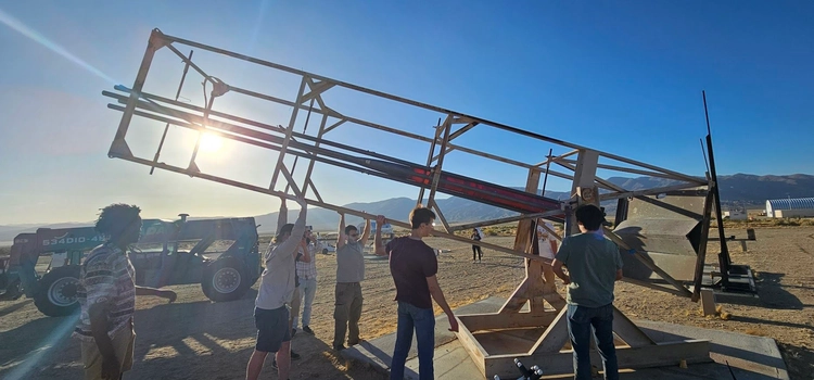Photo of team pushing the launch tower up into its vertical orientation.